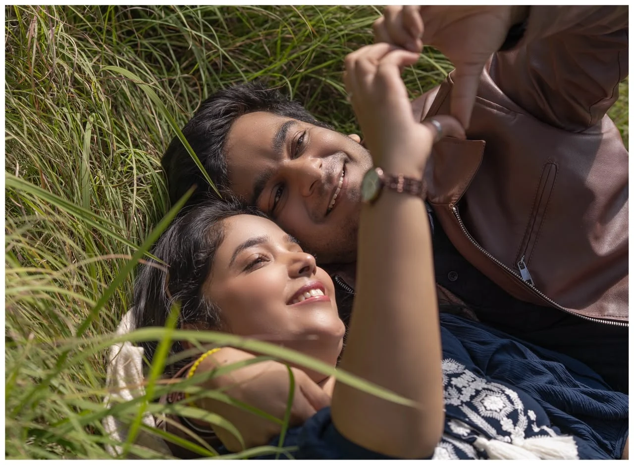 Daksha and Anand lying in the grass, sharing a quiet smile